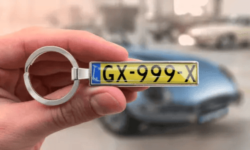 Silver license plate keychain shows personalized numbers while held in hand