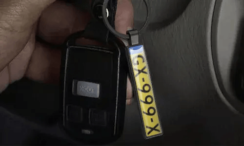 Srebrny brelok z tablicą rejestracyjną wisi na kluczach samochodowych wewnątrz pojazdu