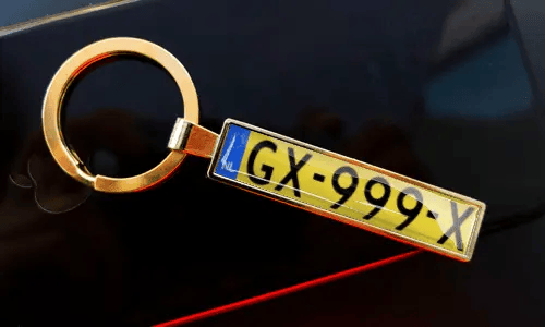 Nummernschild-Schlüsselanhänger an Schlüsseln in der Tasche, mit Auto im Hintergrund