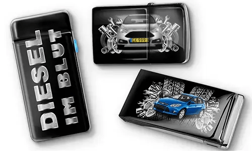 Drei schwarze Feuerzeuge mit Auto-Motiven und metallischen Akzenten. Eines trägt den Text „DIESEL IM BLUT“, die anderen zeigen rote und blaue Autos mit mechanischen Motiven. Ein sportlicher Ton wird vermittelt.