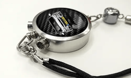 Round car key fob with carbon fiber face, buttons labeled LOCK and UNLOCK, braided black cord attached