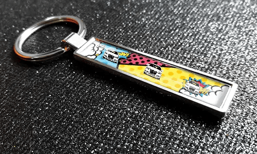 Nøkkelring i tegneseriestil med bilskilt med fargerike pop-art bilgrafikk på en teksturert overflate
