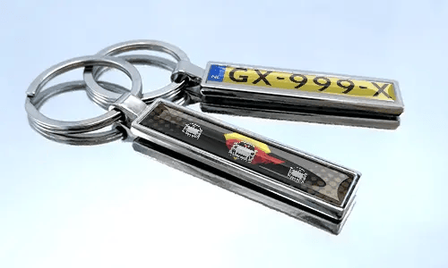 Comic-style license plate keychains with colorful car graphics displayed on a reflective surface