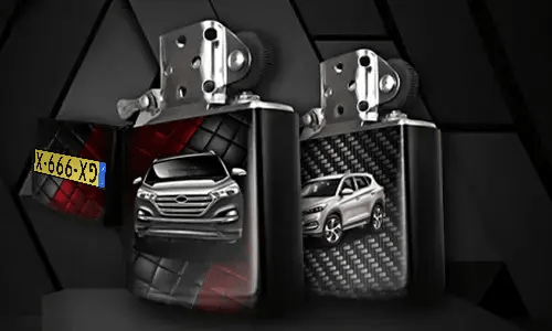 Two metallic lighters with silver SUV designs: one front view on tread background, one side view with carbon texture, small rectangular object in corner