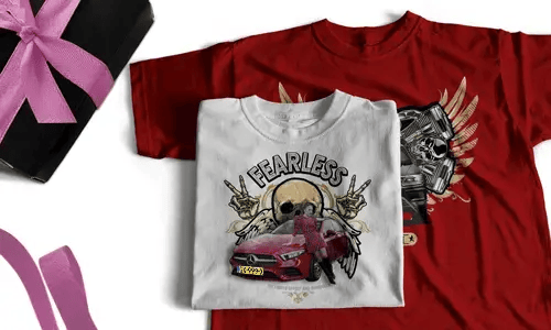 Two T-shirts, one white with FEARLESS, skull, halo, hand signs, red car; one red with winged skull