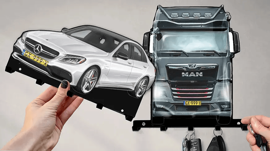 Wandmontierter Schlüsselhalter mit abnehmbaren Formen eines weißen Mercedes-Benz und eines schwarzen MAN-LKWs, jeweils mit Haken für Schlüssel